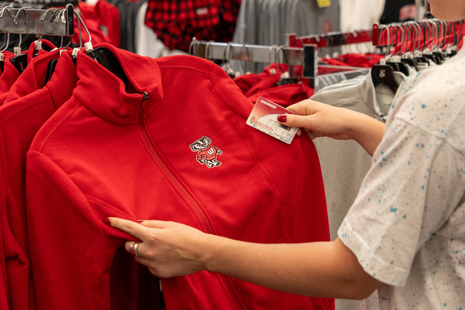 A shopper browsing UW apparel with a Wiscard in their hand.