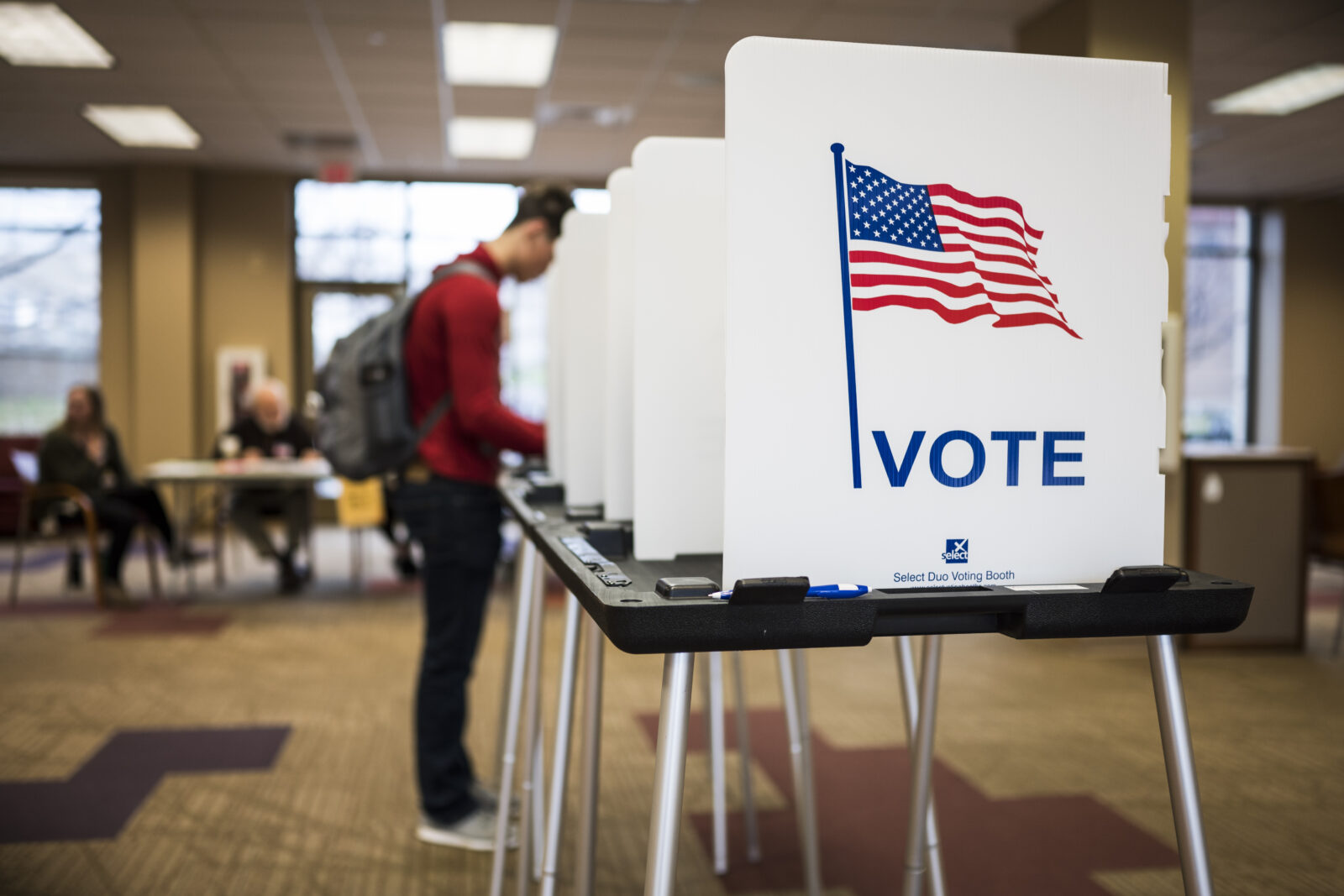 Student filling out an election ballot at a voting booth.